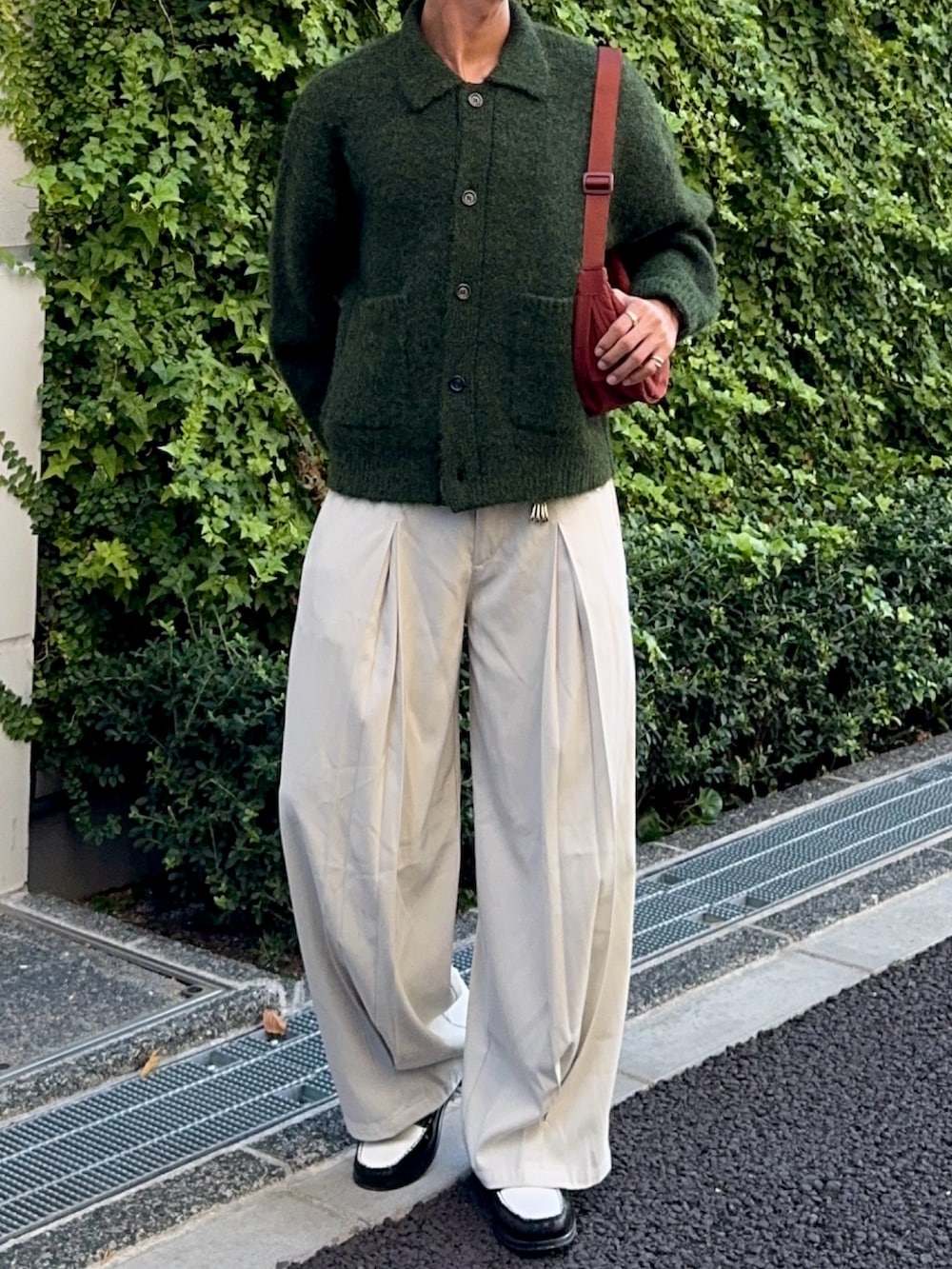 グリーン系のカーディガン/ボレロ、ブラック系のローファー、ホワイト系のスラックスを着用したメンズの秋コーディネートの4枚目の写真