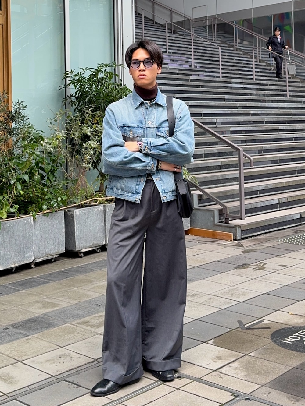 ブルー系のデニムジャケット、グレー系のスラックス、ブラック系のショルダーバッグを着用したメンズの冬コーディネートの5枚目の写真