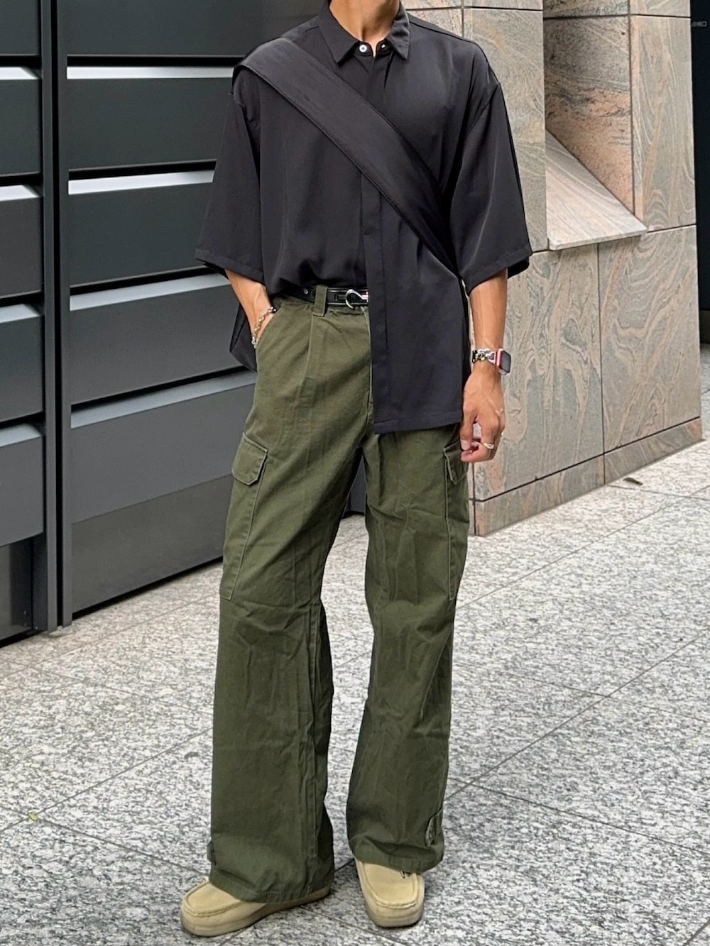 グリーン系のカーゴパンツ、ベージュ系のモカシン/デッキシューズ、ブラック系のシャツ/ブラウスを着用したメンズの夏コーディネートの4枚目の写真