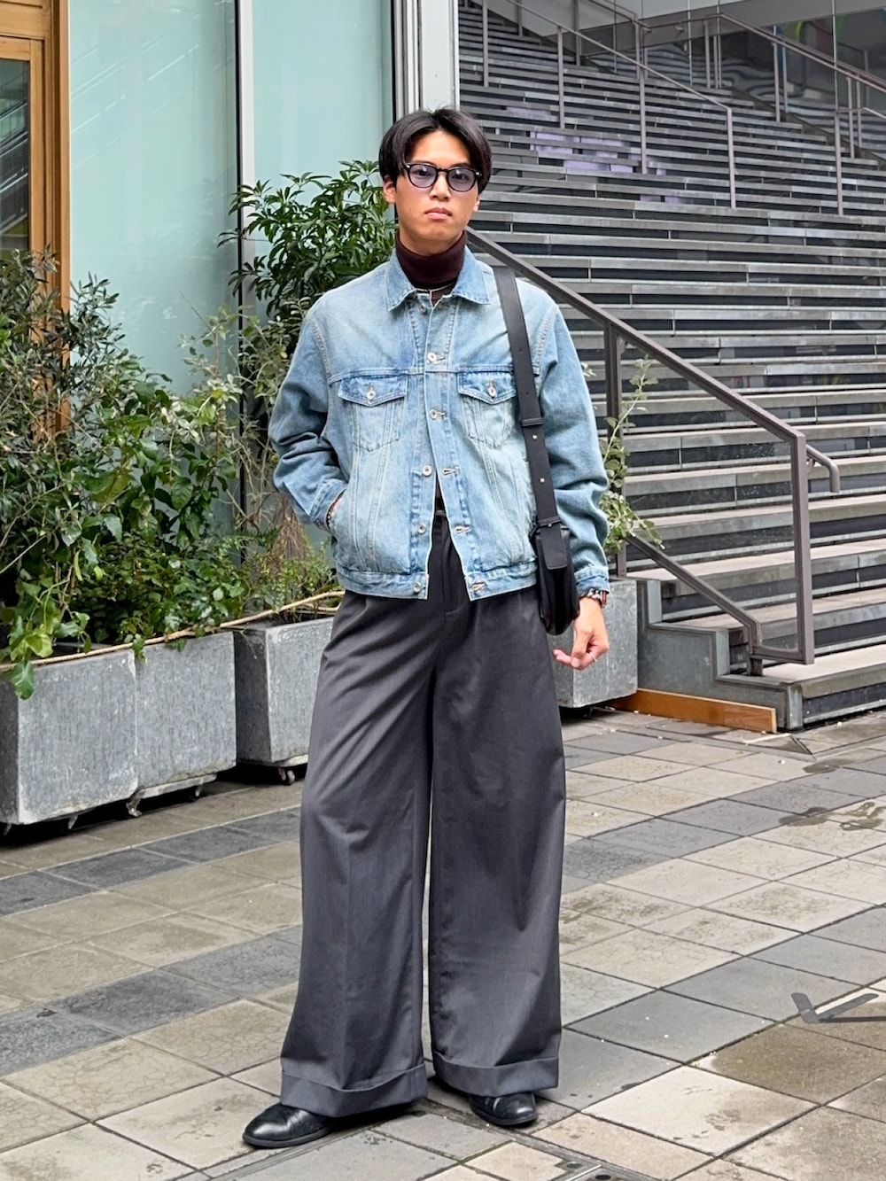 ブルー系のデニムジャケット、グレー系のスラックス、ブラック系のショルダーバッグを着用したメンズの冬コーディネートの3枚目の写真