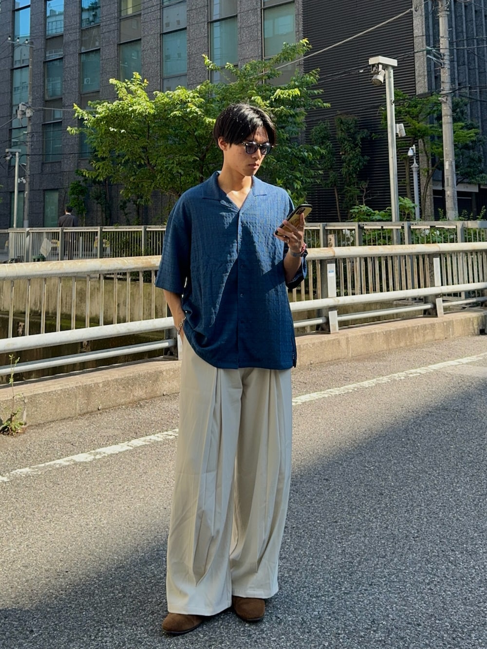 ブルー系のシャツ/ブラウス、ホワイト系のスラックス、ブラック系のハンドバッグを着用したメンズの春コーディネートの3枚目の写真