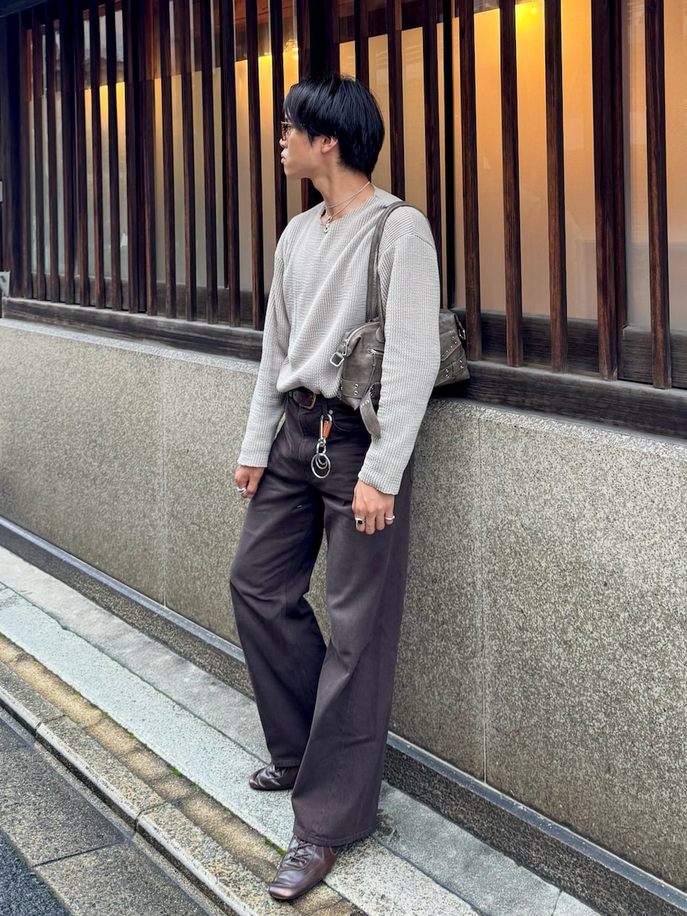 グリーン系のTシャツ/カットソー、ブラウン系のデニムパンツ、ブラウン系のショルダーバッグを着用したメンズの秋コーディネートの3枚目の写真