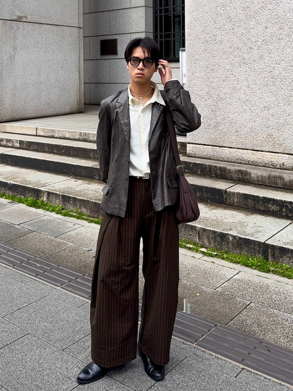 ブラック系のテーラードジャケット、ブラウン系のスラックス、ホワイト系のシャツ/ブラウスを着用したメンズの春コーディネートの5枚目の写真