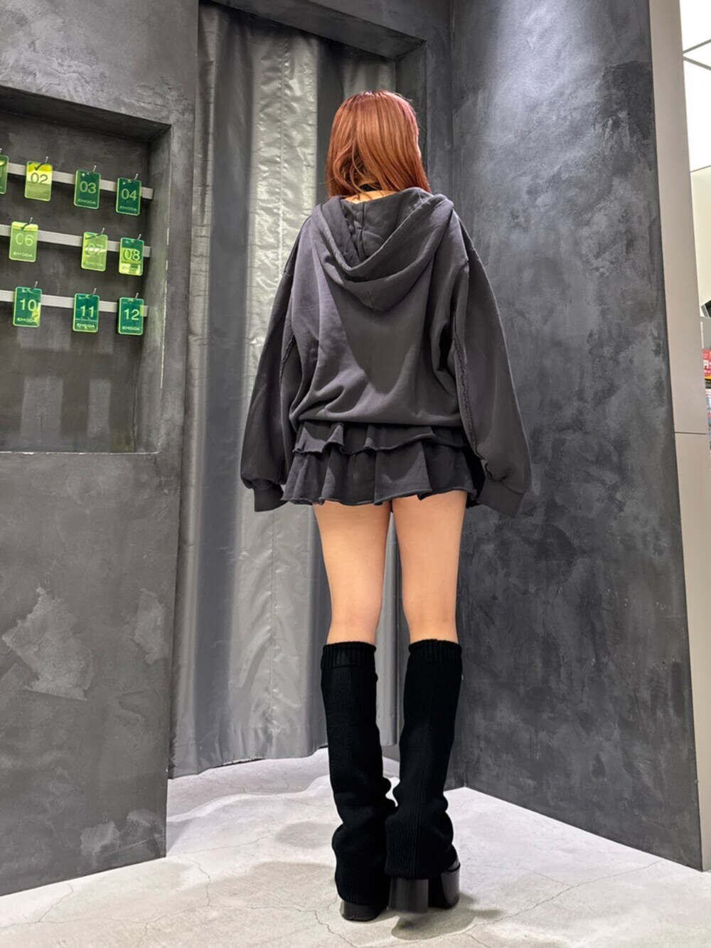 グレー系のパーカー、グレー系のスカート、ブラック系のブーツを着用したレディースの秋コーディネートの3枚目の写真