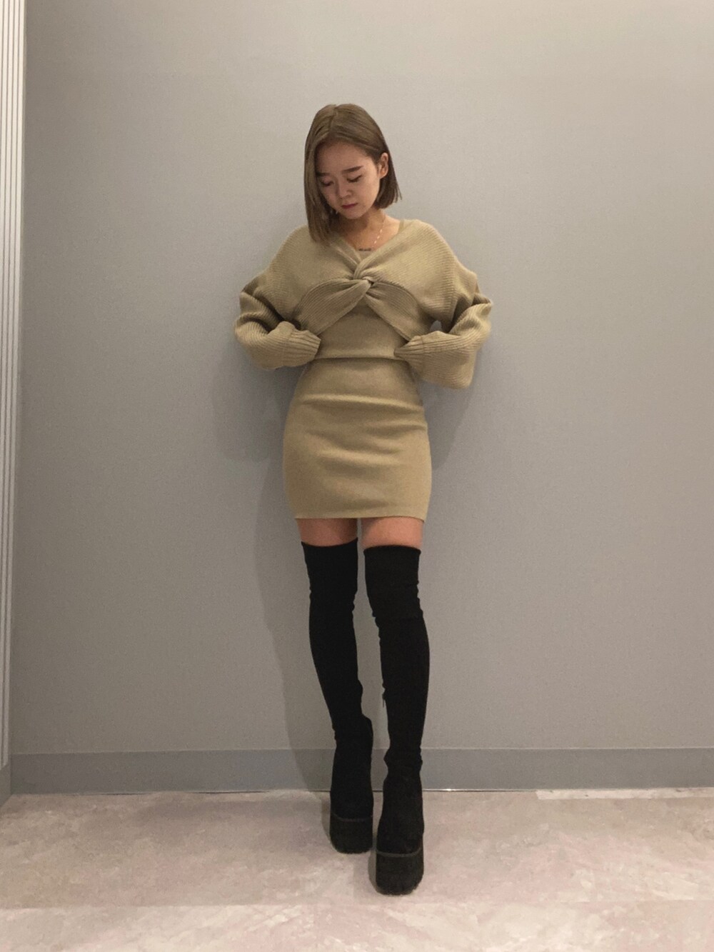 ベージュ系のワンピース、ブラック系のブーツを着用したレディースの秋コーディネートの2枚目の写真