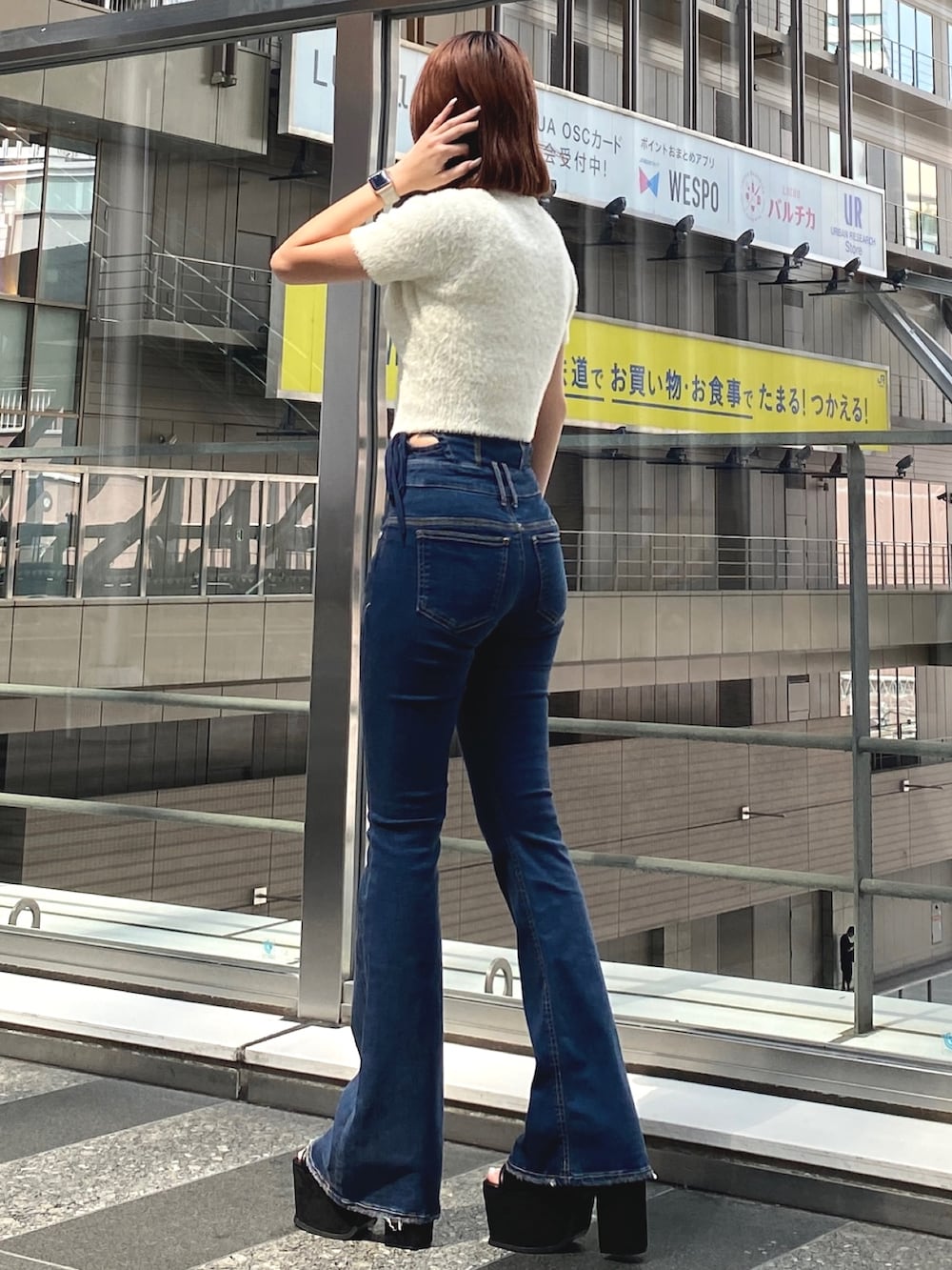 ホワイト系のニット/セーター、ブルー系のデニムパンツ、ブラック系のサンダルを着用したレディースの夏コーディネートの2枚目の写真