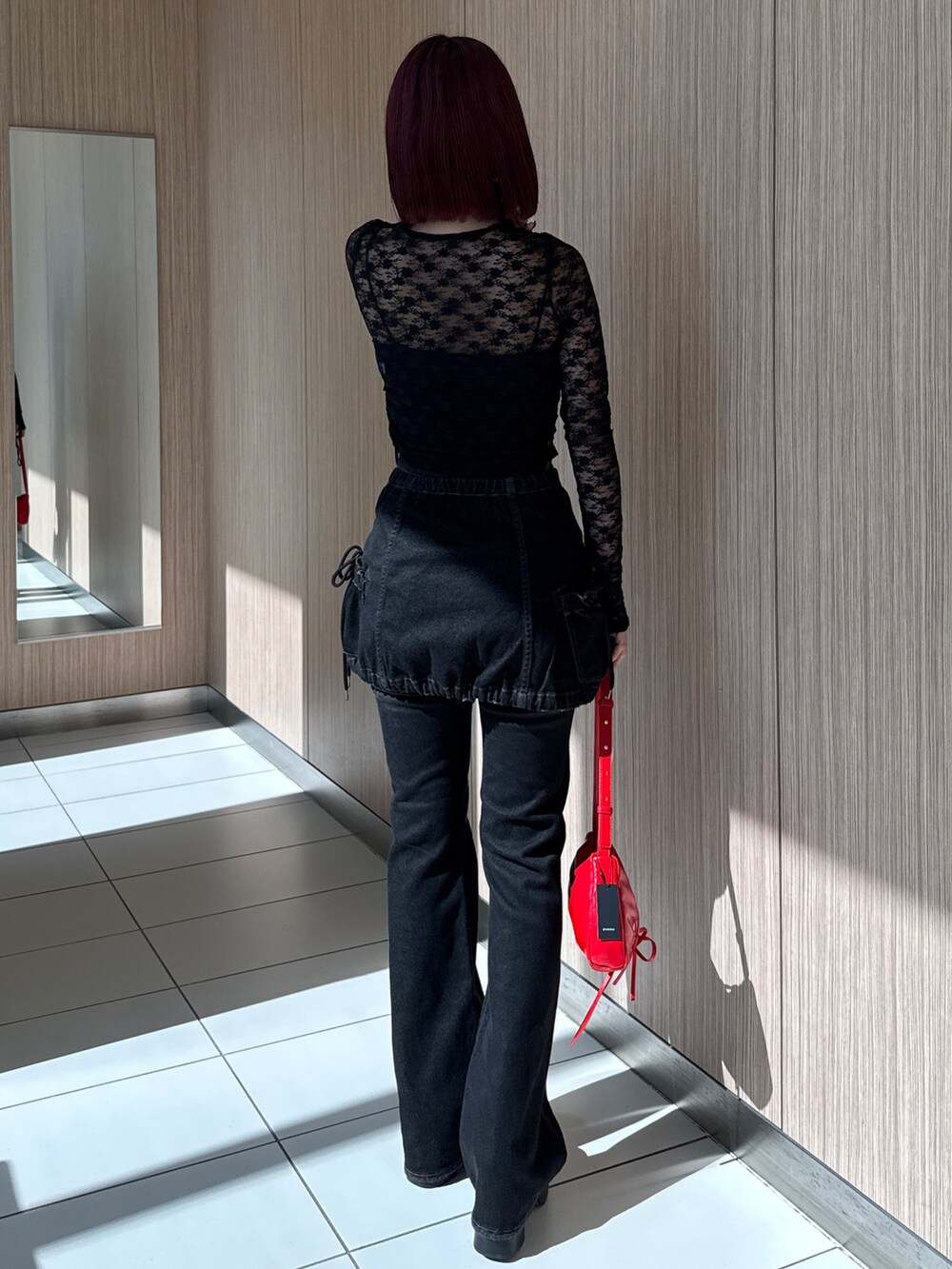 ブラック系のTシャツ/カットソー、ブラック系のデニムパンツ、レッド系のショルダーバッグを着用したレディースの秋コーディネートの3枚目の写真