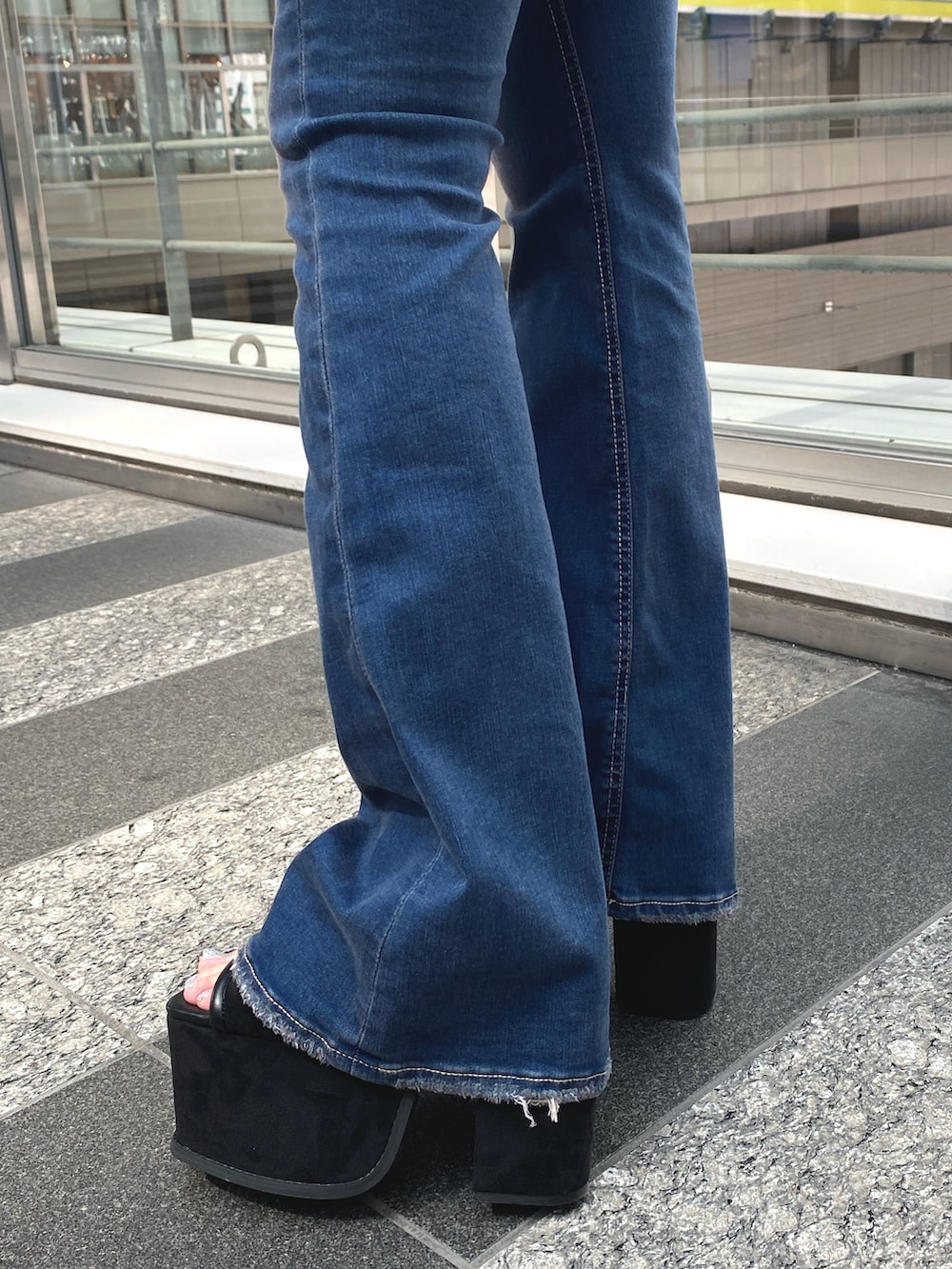 ホワイト系のニット/セーター、ブルー系のデニムパンツ、ブラック系のサンダルを着用したレディースの夏コーディネートの4枚目の写真