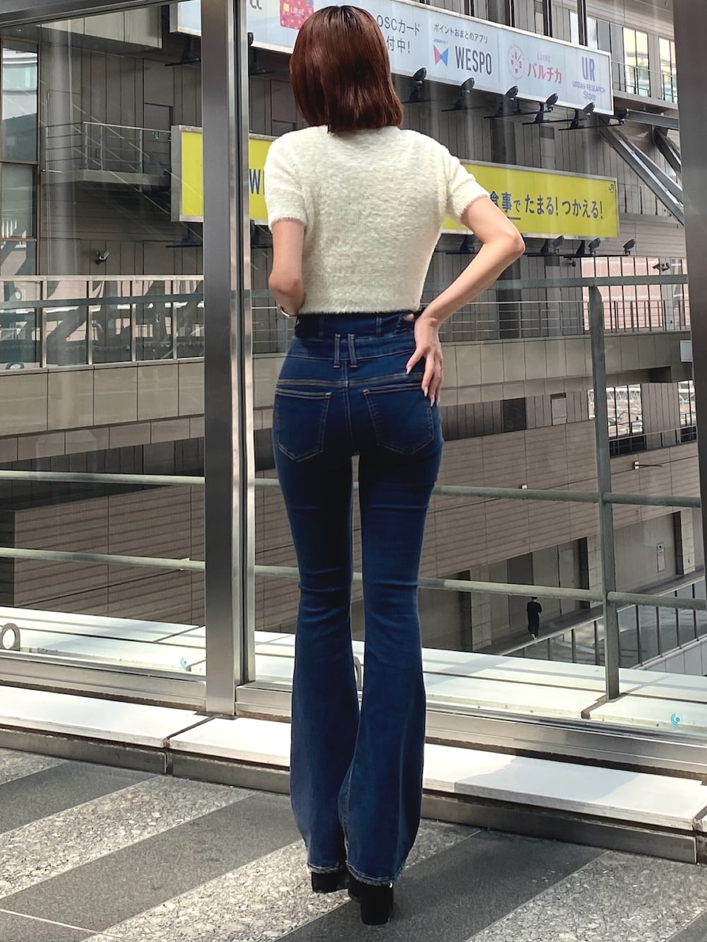 ホワイト系のニット/セーター、ブルー系のデニムパンツ、ブラック系のサンダルを着用したレディースの夏コーディネートの3枚目の写真