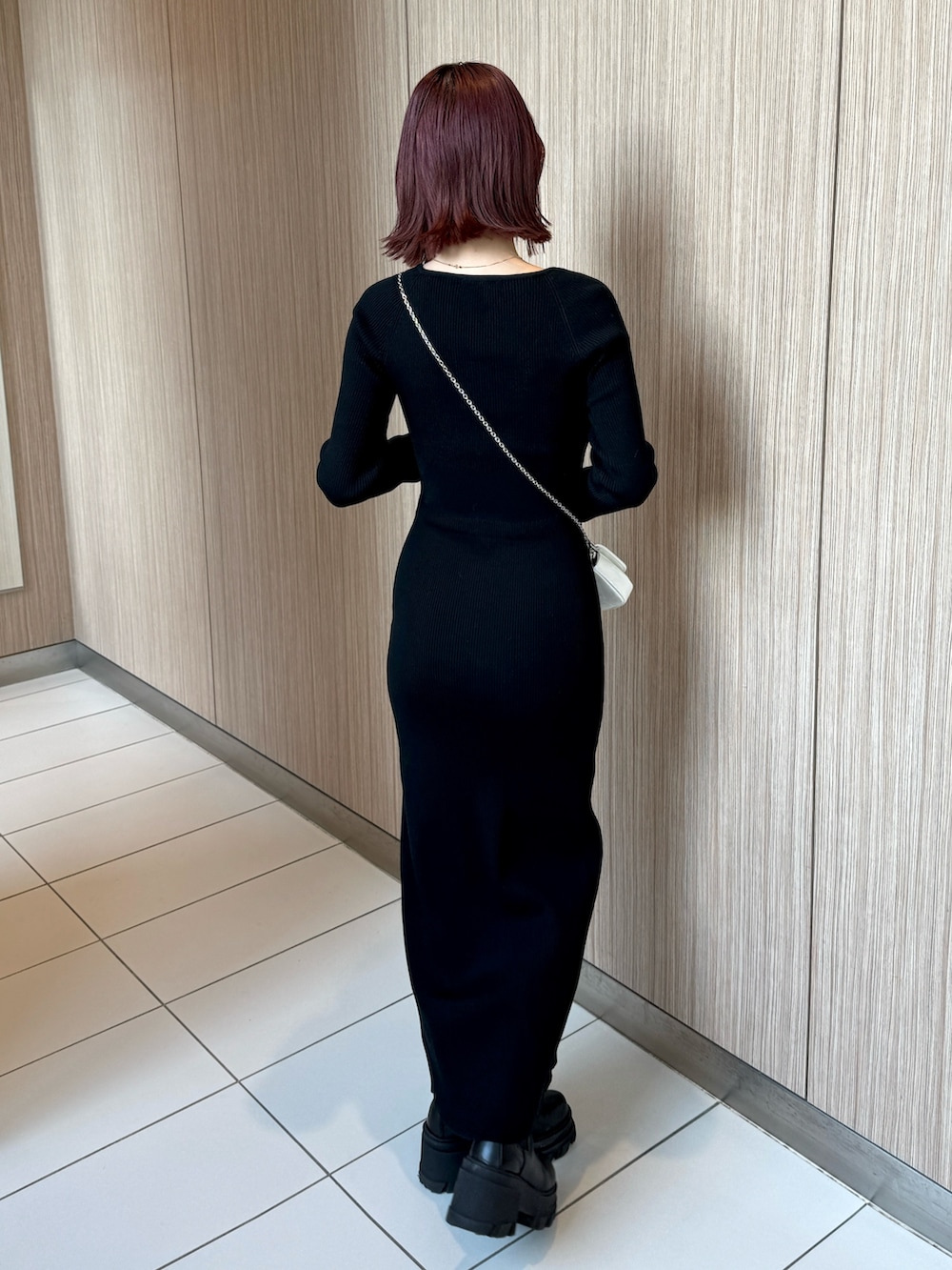 ブラック系のワンピース、ブラック系のブーツ、ホワイト系のスマホケース/カバーを着用したレディースの冬コーディネートの2枚目の写真