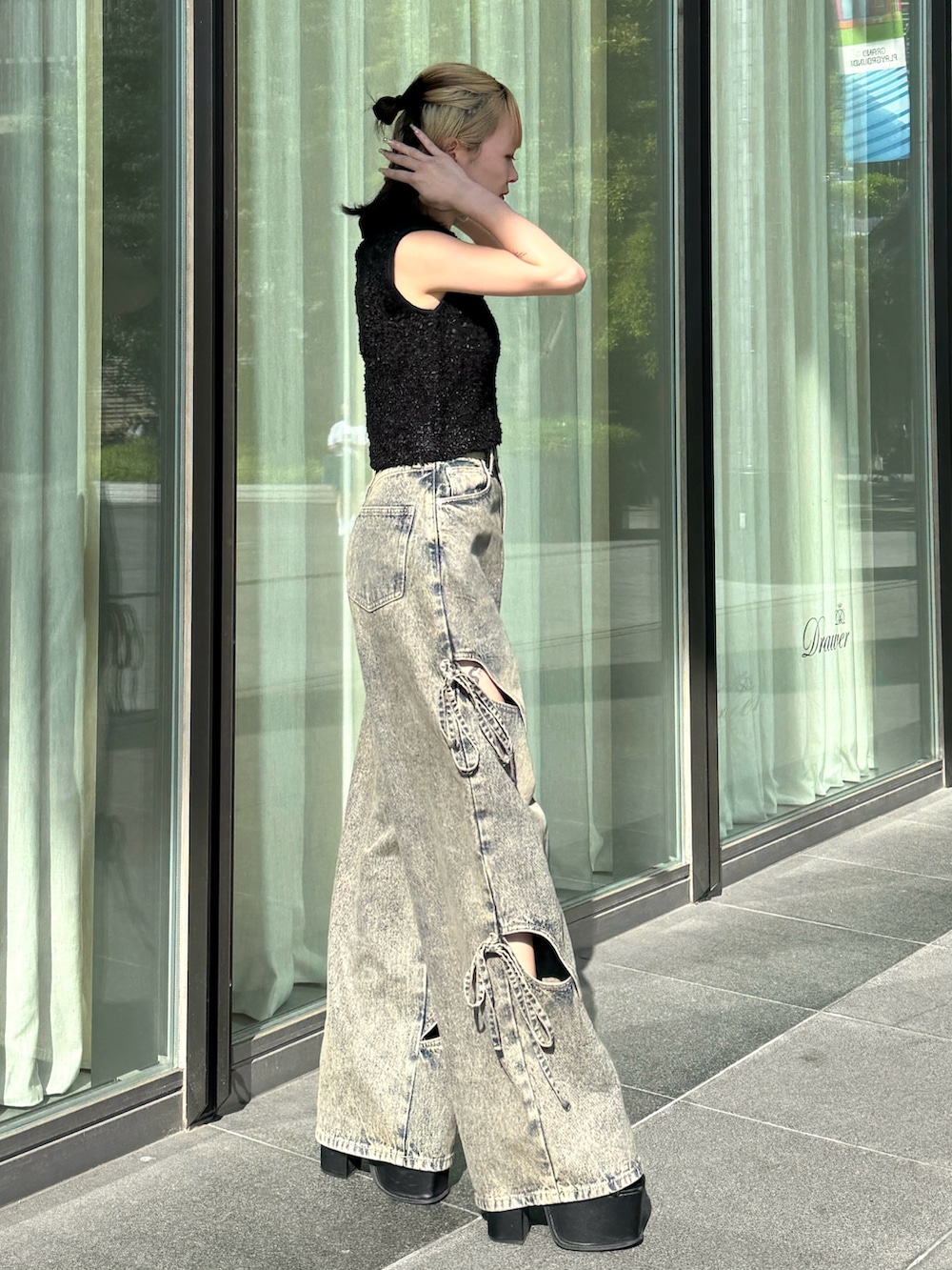 ブラック系のニット/セーター、ブルー系のデニムパンツ、ブラック系のサンダルを着用したレディースの夏コーディネートの2枚目の写真