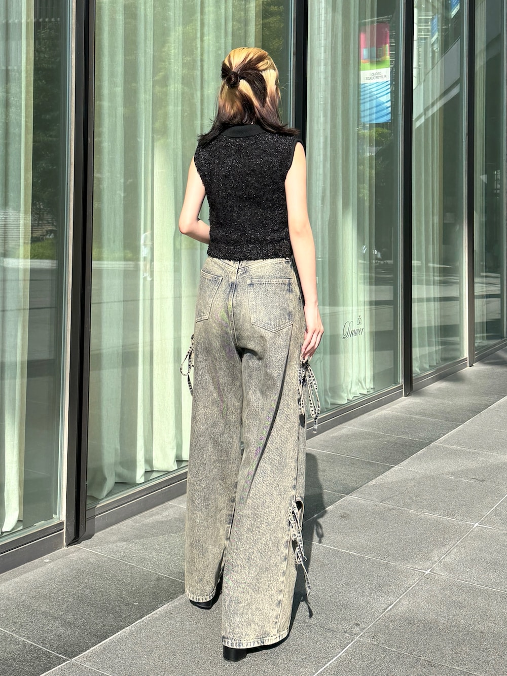 ブラック系のニット/セーター、ブルー系のデニムパンツ、ブラック系のサンダルを着用したレディースの夏コーディネートの3枚目の写真