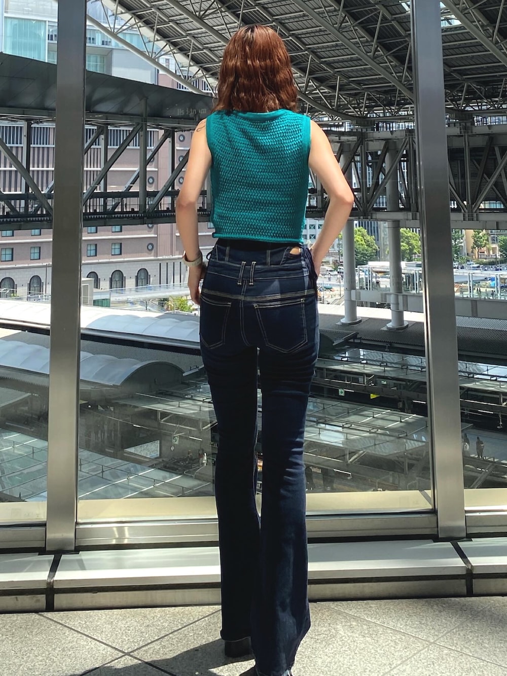 グリーン系のタンクトップ、ホワイト系のキャミソール、ブルー系のデニムパンツを着用したレディースの夏コーディネートの3枚目の写真