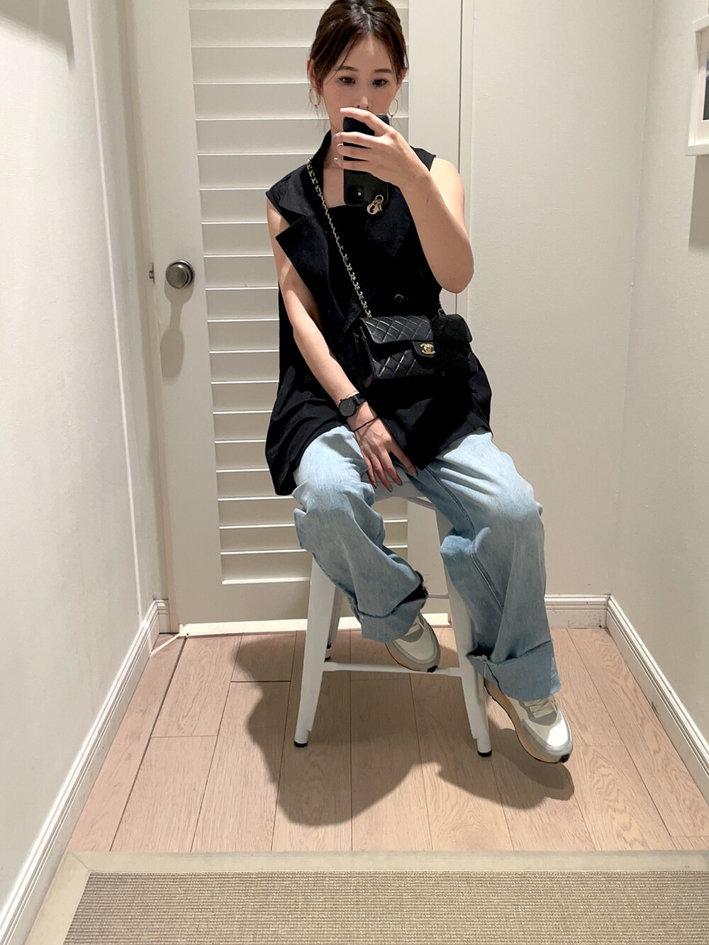 ブラック系のショルダーバッグ、ブルー系のデニムパンツ、ブラック系のベストを着用したレディースの秋コーディネートの3枚目の写真