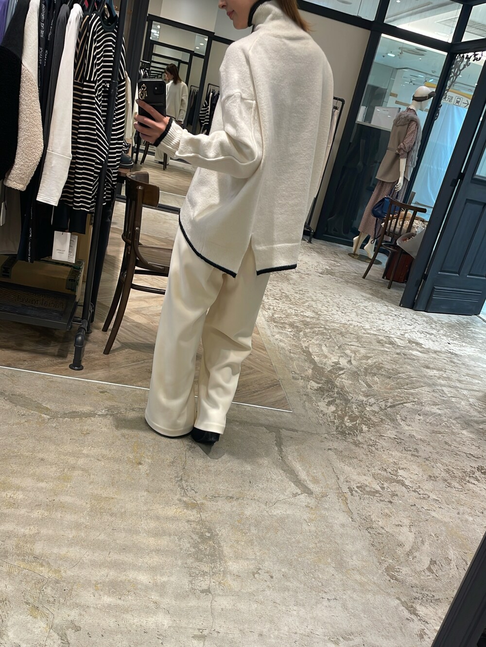 ホワイト系のニット/セーター、ホワイト系のその他パンツ、ブラック系のブーツを着用したレディースの秋コーディネートの2枚目の写真