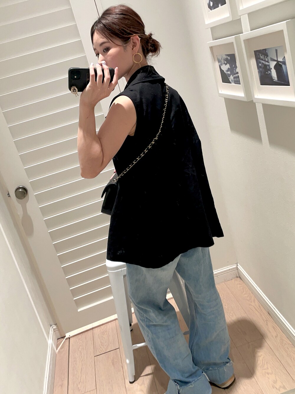 ブラック系のショルダーバッグ、ブルー系のデニムパンツ、ブラック系のベストを着用したレディースの秋コーディネートの2枚目の写真