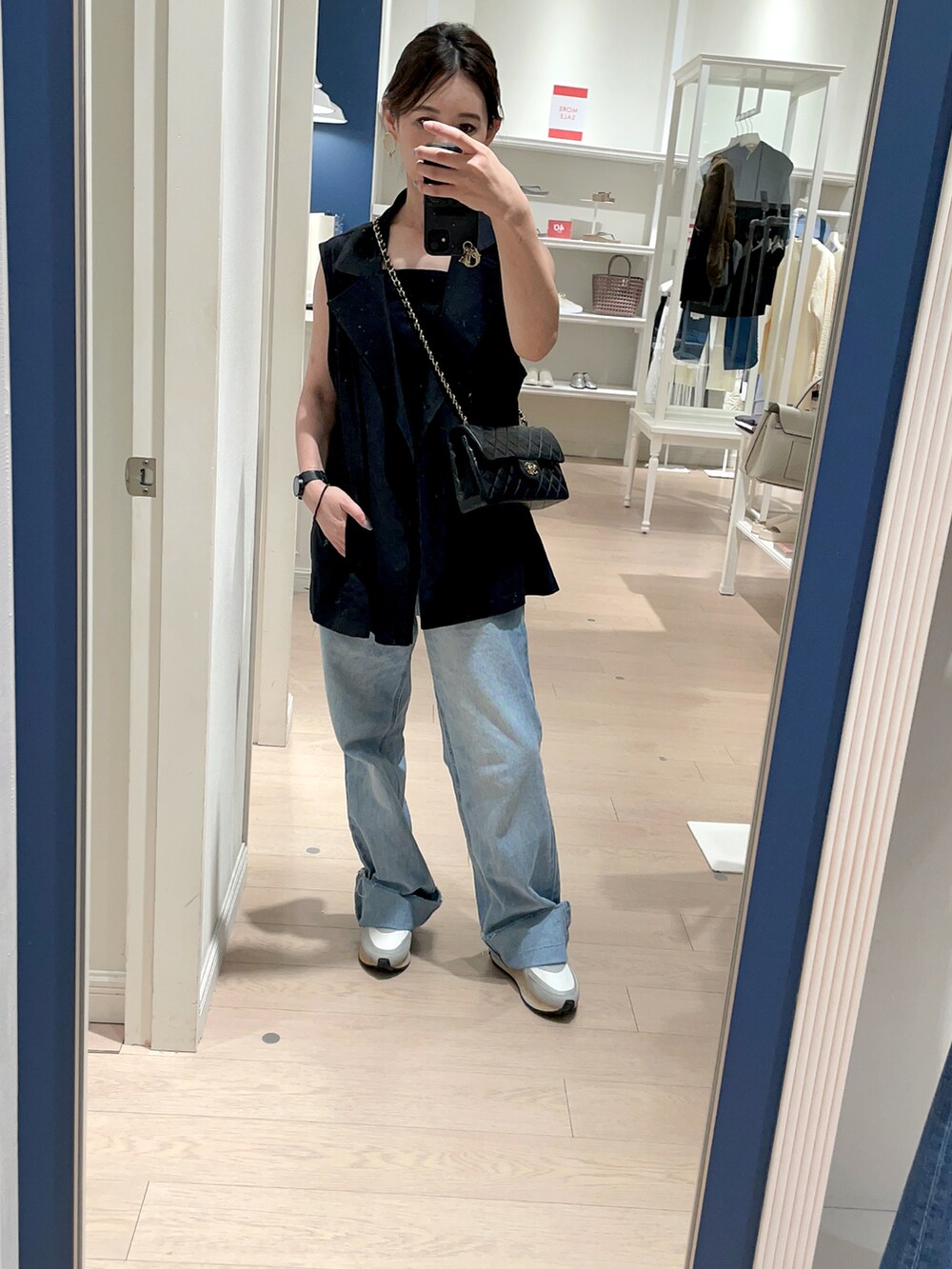 ブラック系のショルダーバッグ、ブルー系のデニムパンツ、ブラック系のベストを着用したレディースの秋コーディネートの4枚目の写真