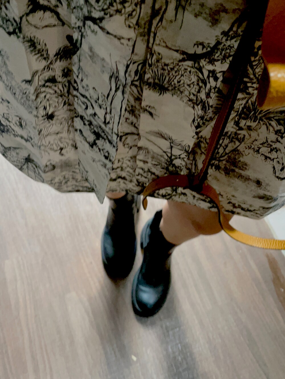 イエロー系のショルダーバッグ、ホワイト系のシャツワンピース、ブラック系のブーツを着用したレディースの秋コーディネートの2枚目の写真