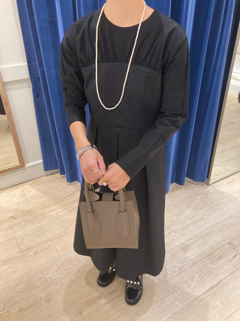 ブルー系のワンピース、ベージュ系のトートバッグ、ブラック系のレインシューズを着用したレディースの秋コーディネートの5枚目の写真