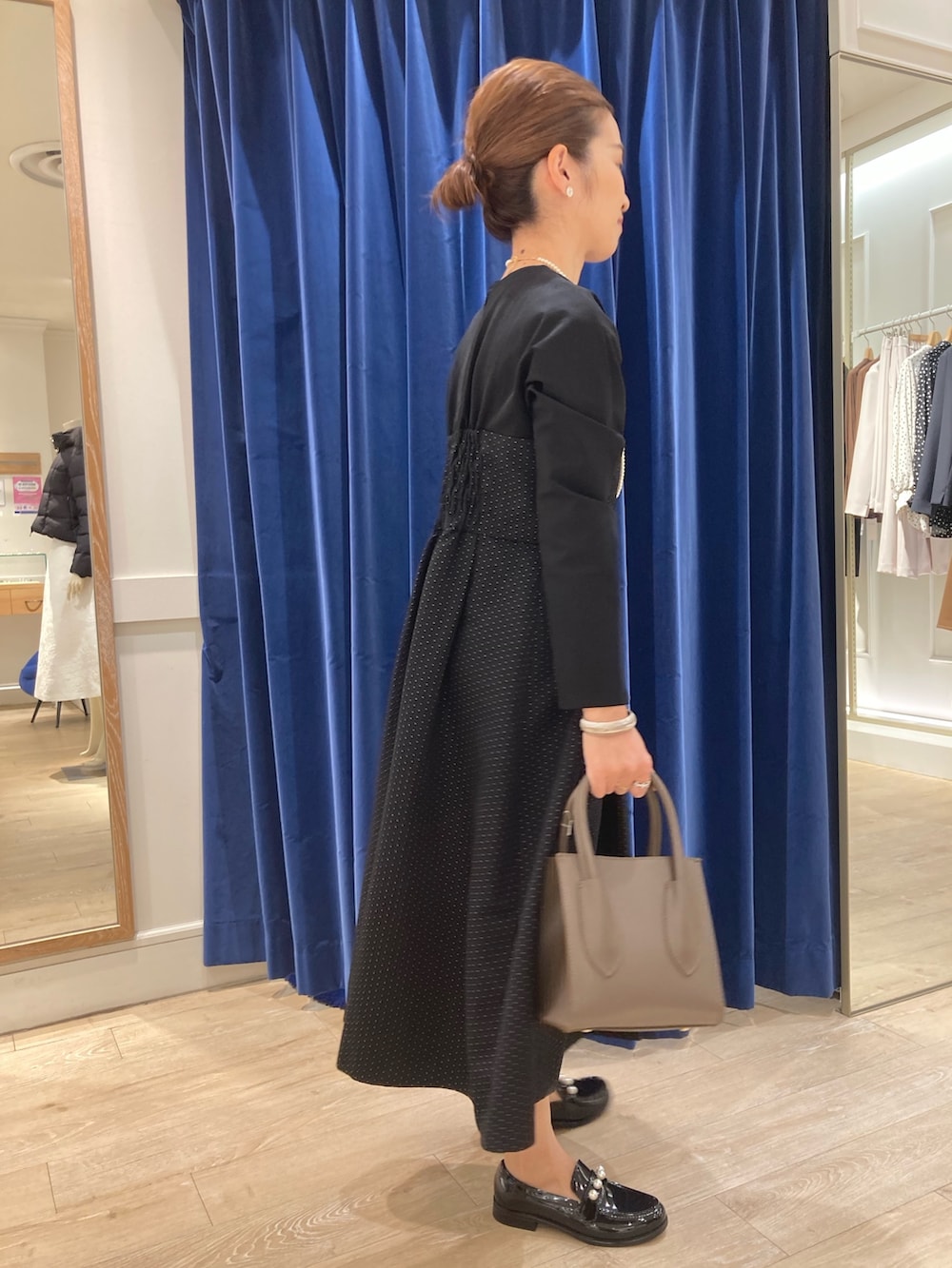 ブルー系のワンピース、ベージュ系のトートバッグ、ブラック系のレインシューズを着用したレディースの秋コーディネートの2枚目の写真