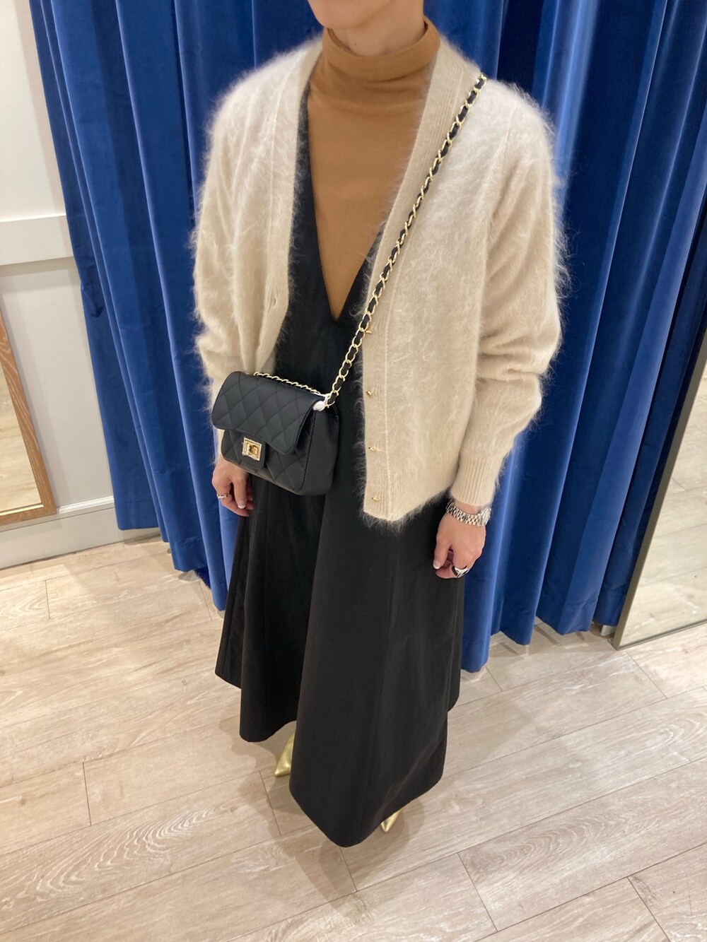 ブルー系のワンピース、ベージュ系のカーディガン/ボレロ、ゴールド系のニット/セーターを着用したレディースの冬コーディネートの5枚目の写真