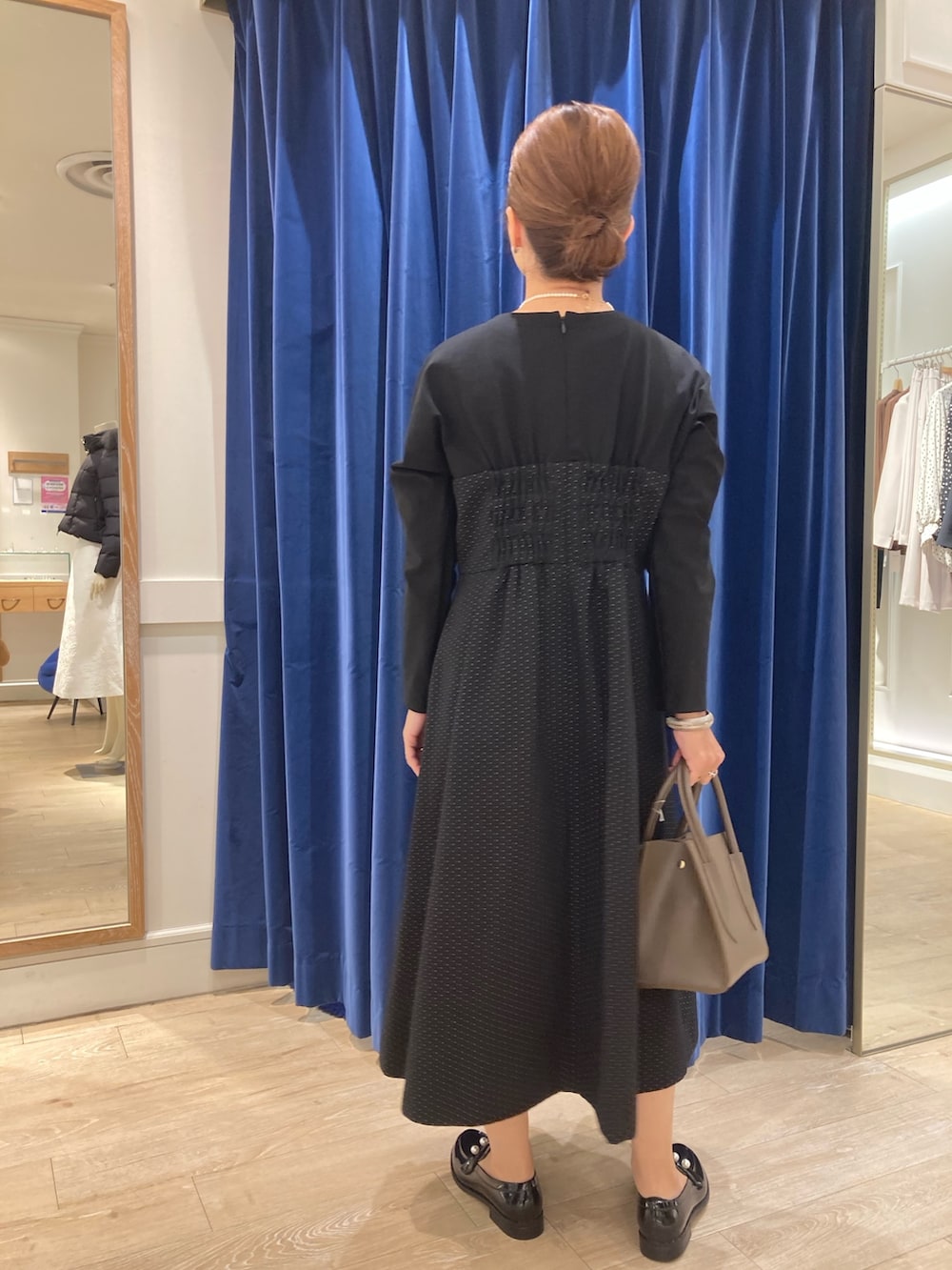 ブルー系のワンピース、ベージュ系のトートバッグ、ブラック系のレインシューズを着用したレディースの秋コーディネートの3枚目の写真