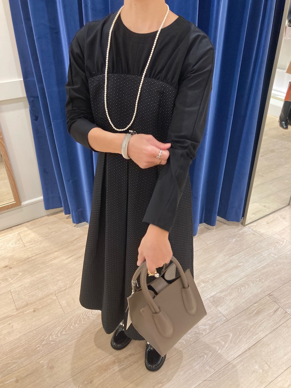 ブルー系のワンピース、ベージュ系のトートバッグ、ブラック系のレインシューズを着用したレディースの秋コーディネートの4枚目の写真