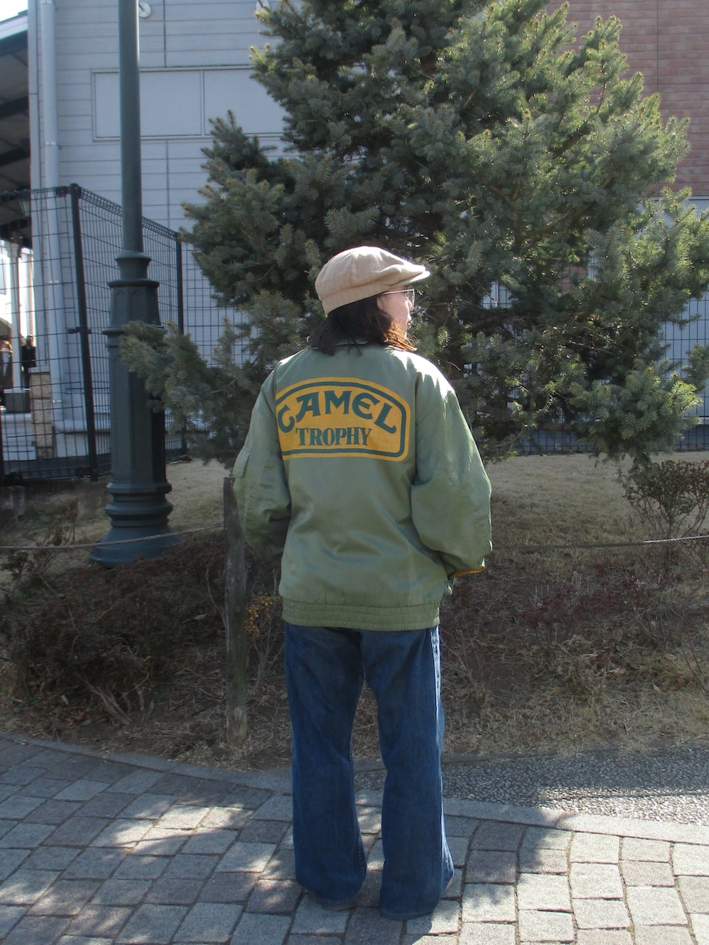 ブラウン系のスニーカー、グリーン系のスタジャン、ブルー系のデニムパンツを着用したレディースの冬コーディネートの2枚目の写真