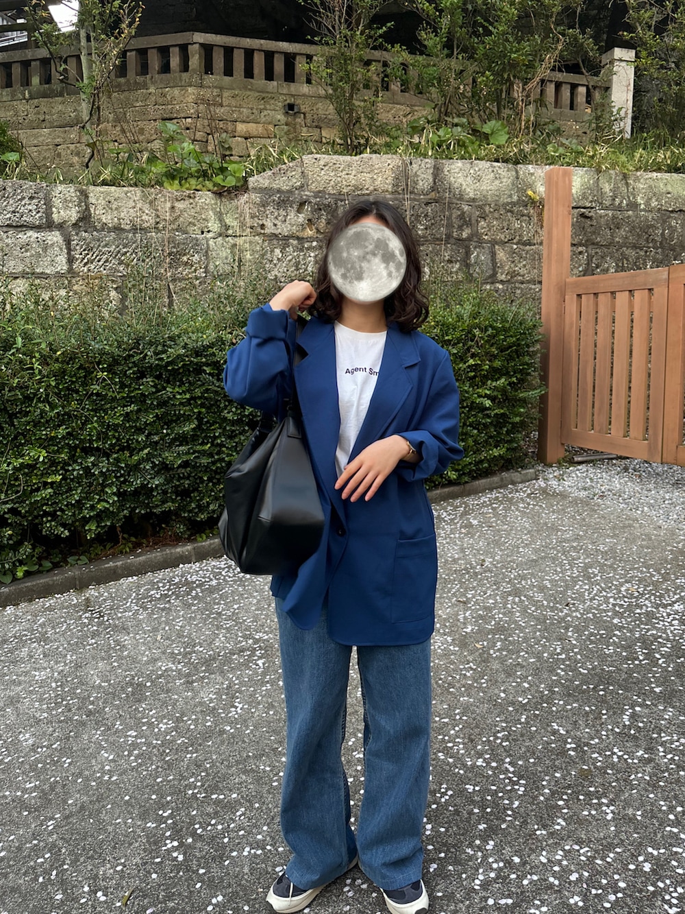 ブラック系のショルダーバッグ、ブルー系のデニムパンツ、ブラック系のスニーカーを着用したレディースの春コーディネートの2枚目の写真