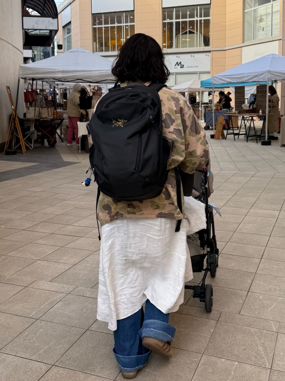 ブラウン系のスニーカー、ホワイト系のワンピース、ブラック系のバックパック/リュックを着用したレディースの春コーディネートの2枚目の写真