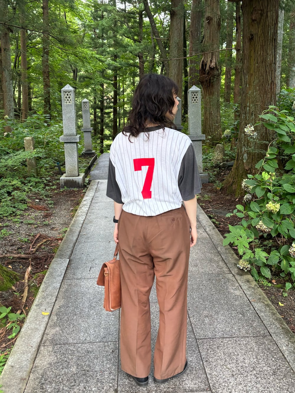 ブラウン系のバッグ、ブラック系のローファー、ブラック系のアナログ腕時計を着用したレディースの夏コーディネートの2枚目の写真