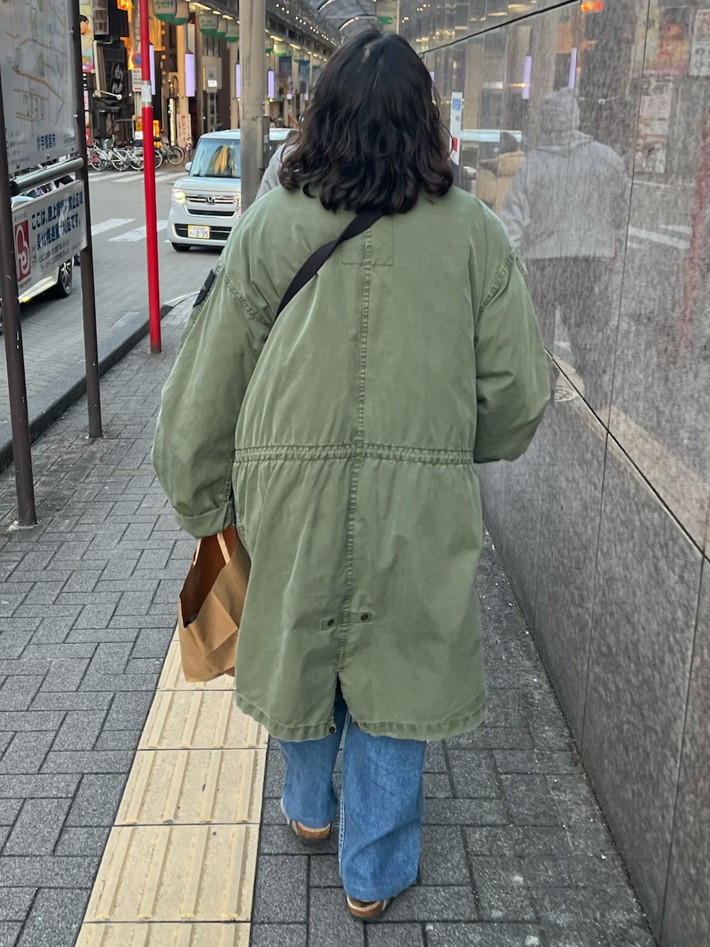 ブラック系のショルダーバッグ、グレー系のシューズ、グリーン系のモッズコートを着用したレディースの春コーディネートの2枚目の写真