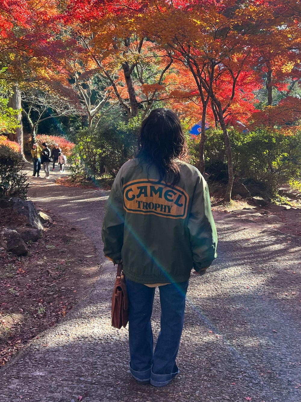 ブラウン系のバッグ、ブラック系のブーツ、ブルー系のデニムパンツを着用したレディースの冬コーディネートの2枚目の写真