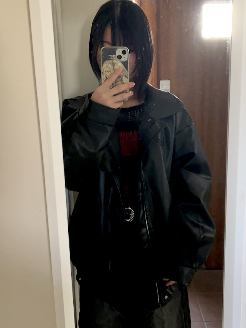 レッド系のニット/セーター、ブラック系のデニムパンツ、ブラック系のベルトを着用したレディースの春コーディネートの2枚目の写真