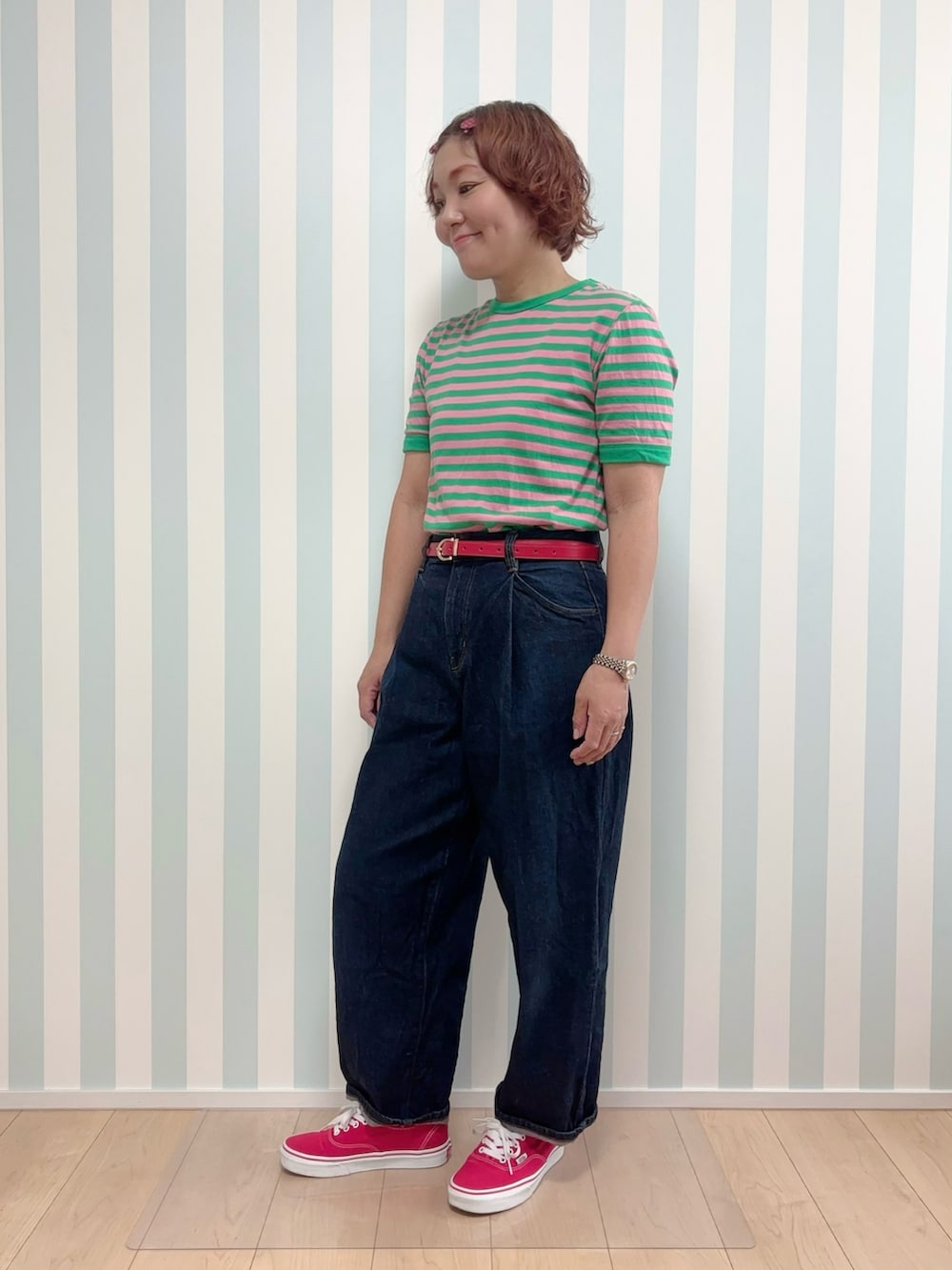 レッド系のスニーカー、グリーン系のTシャツ/カットソー、ブルー系のデニムパンツを着用したレディースの夏コーディネートの3枚目の写真