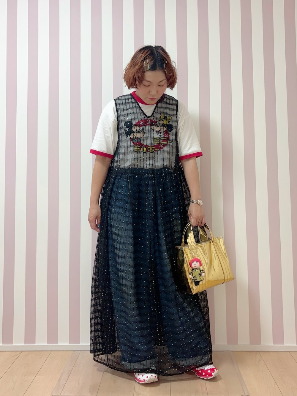 ブルー系のデニムパンツ、ブラック系のワンピース、ゴールド系のトートバッグを着用したレディースの夏コーディネートの2枚目の写真