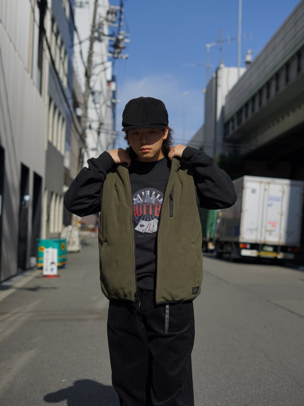 グリーン系のベスト、ブラック系のスウェット、ブラック系のその他パンツを着用したメンズの秋コーディネートの4枚目の写真