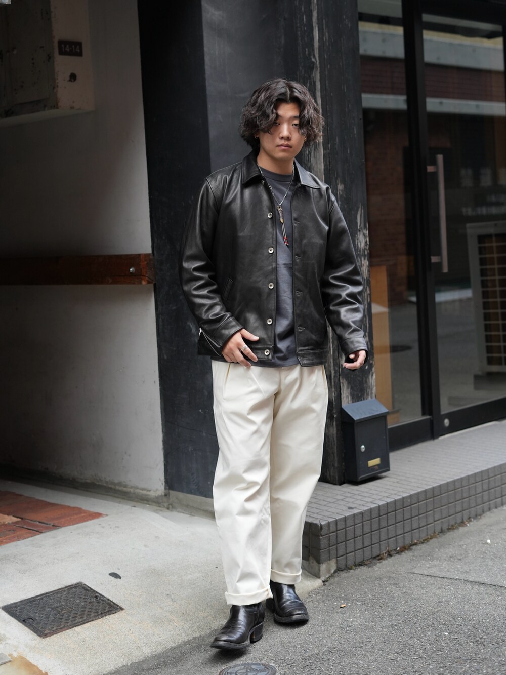 グレー系のTシャツ/カットソー、ブラック系のライダースジャケット、ホワイト系のチノパンツを着用したメンズの秋コーディネートの2枚目の写真