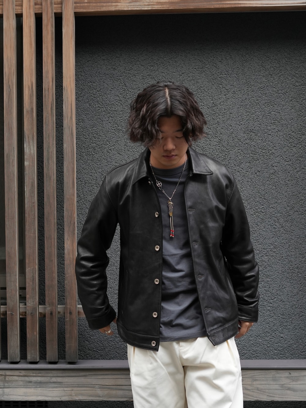 グレー系のTシャツ/カットソー、ブラック系のライダースジャケット、ホワイト系のチノパンツを着用したメンズの秋コーディネートの3枚目の写真