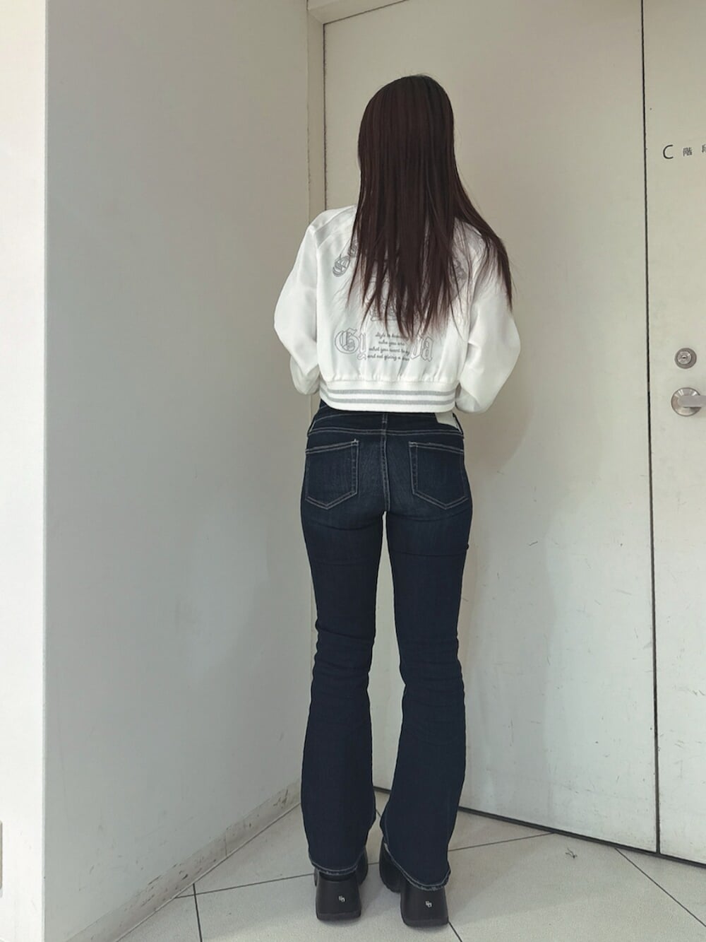 ブルー系のデニムパンツ、ブラック系のサンダル、ホワイト系のブルゾンを着用したレディースの春コーディネートの3枚目の写真