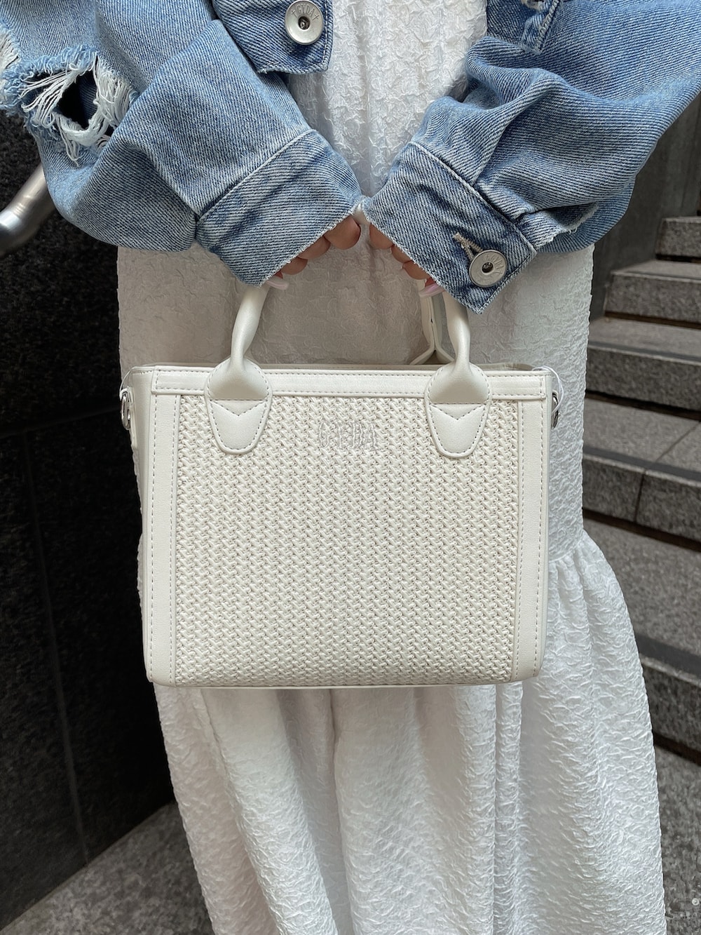 ブルー系のデニムジャケット、ホワイト系のサンダル、ホワイト系のハンドバッグを着用したレディースの春コーディネートの8枚目の写真