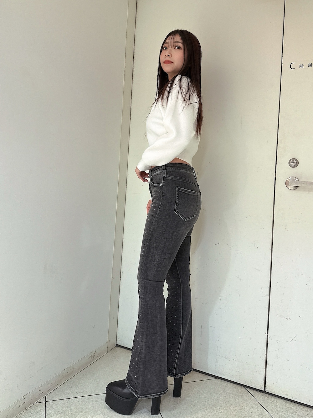 ブラック系のデニムパンツ、ブラック系のブーツ、ホワイト系のニット/セーターを着用したレディースの冬コーディネートの2枚目の写真