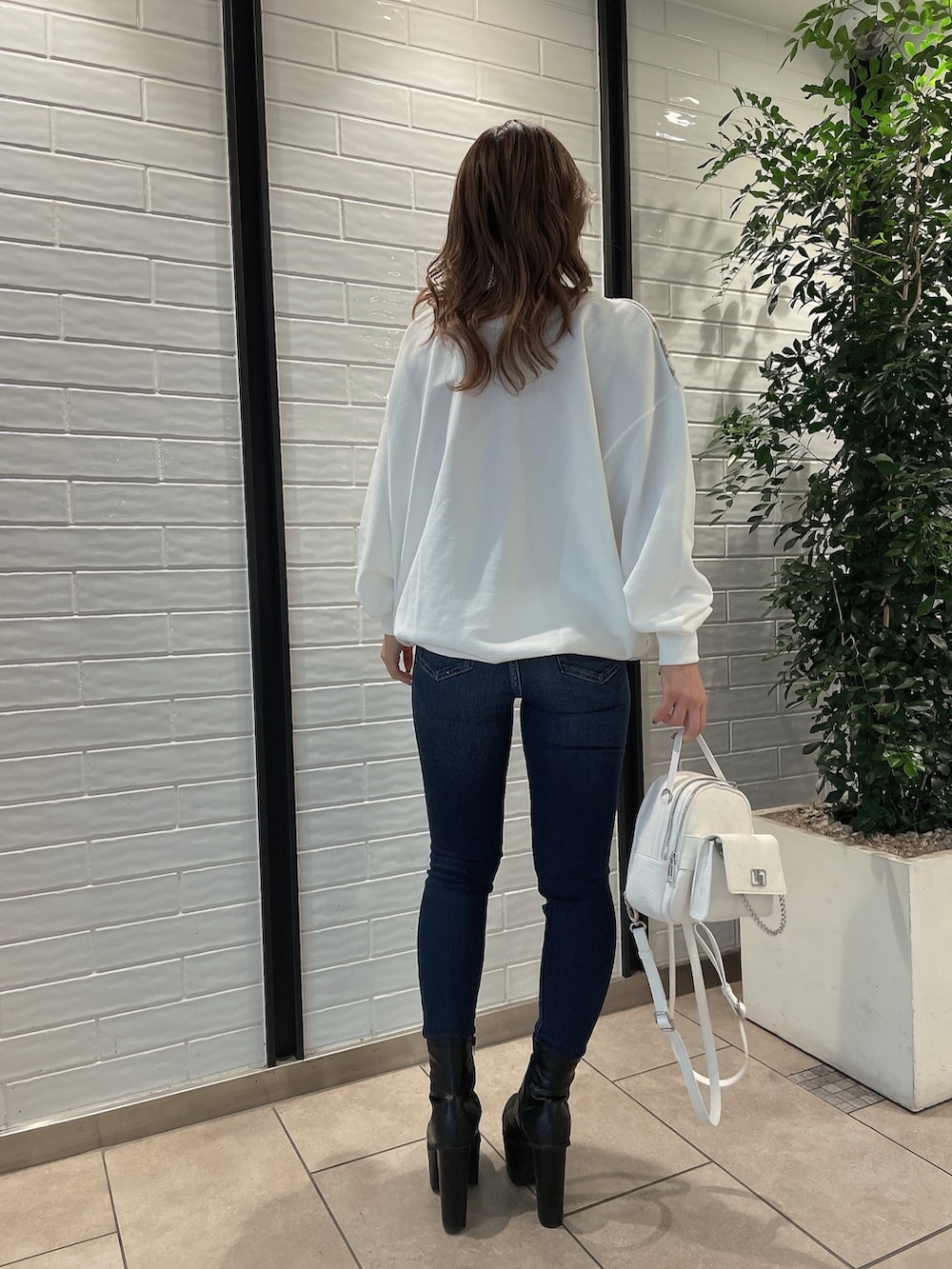 ホワイト系のTシャツ/カットソー、ホワイト系のバックパック/リュック、ブルー系のデニムパンツを着用したレディースの冬コーディネートの3枚目の写真