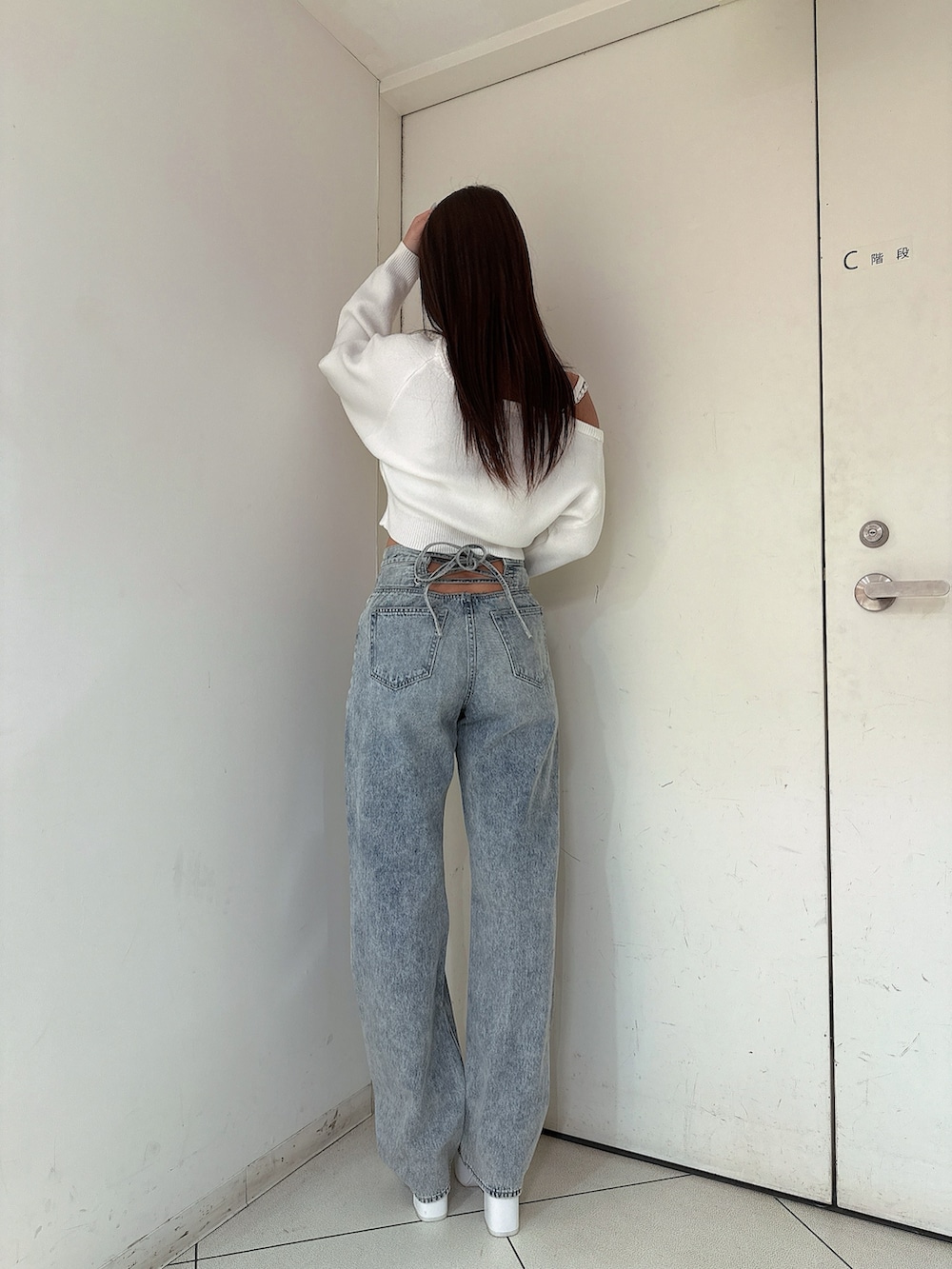 ホワイト系のニット/セーター、ブルー系のデニムパンツ、ホワイト系のパンプスを着用したレディースの冬コーディネートの3枚目の写真