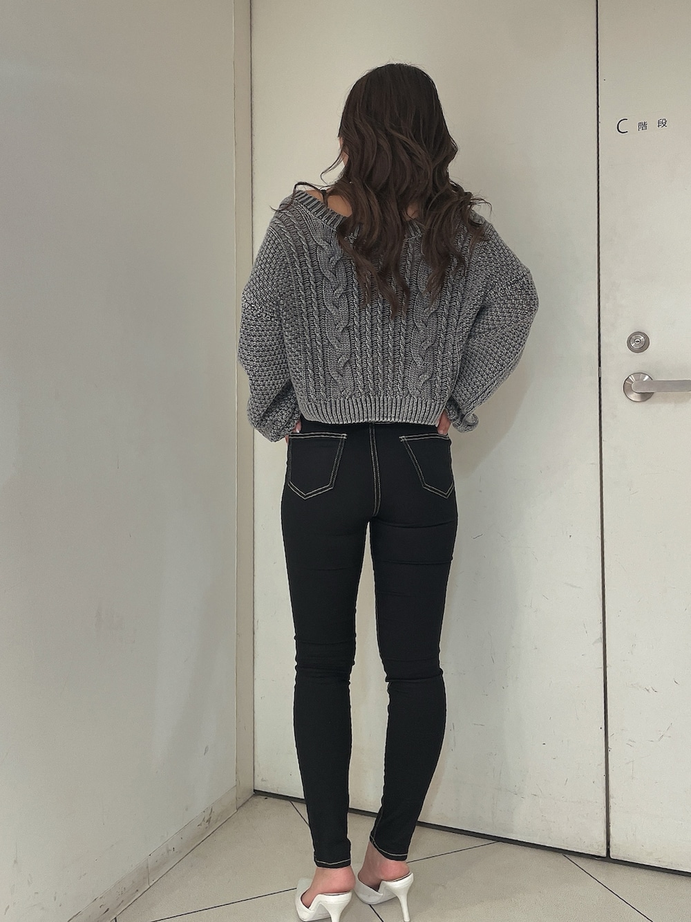 グレー系のニット/セーター、ブラック系のデニムパンツ、ホワイト系のパンプスを着用したレディースの夏コーディネートの3枚目の写真