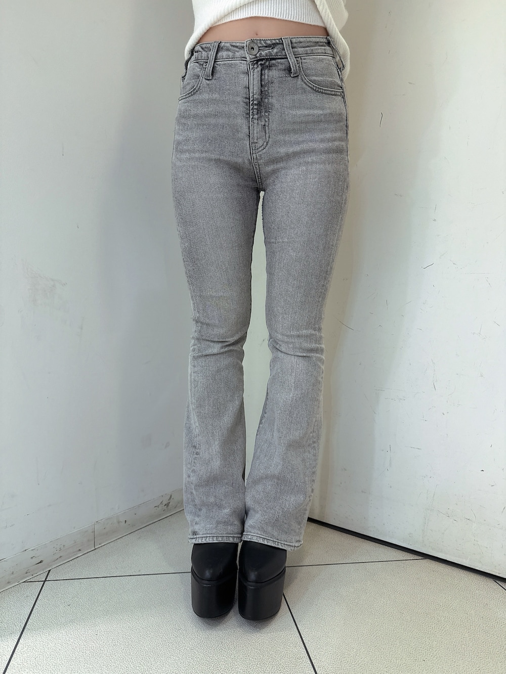 グレー系のデニムパンツ、ブラック系のブーツ、ホワイト系のニット/セーターを着用したレディースの秋コーディネートの8枚目の写真