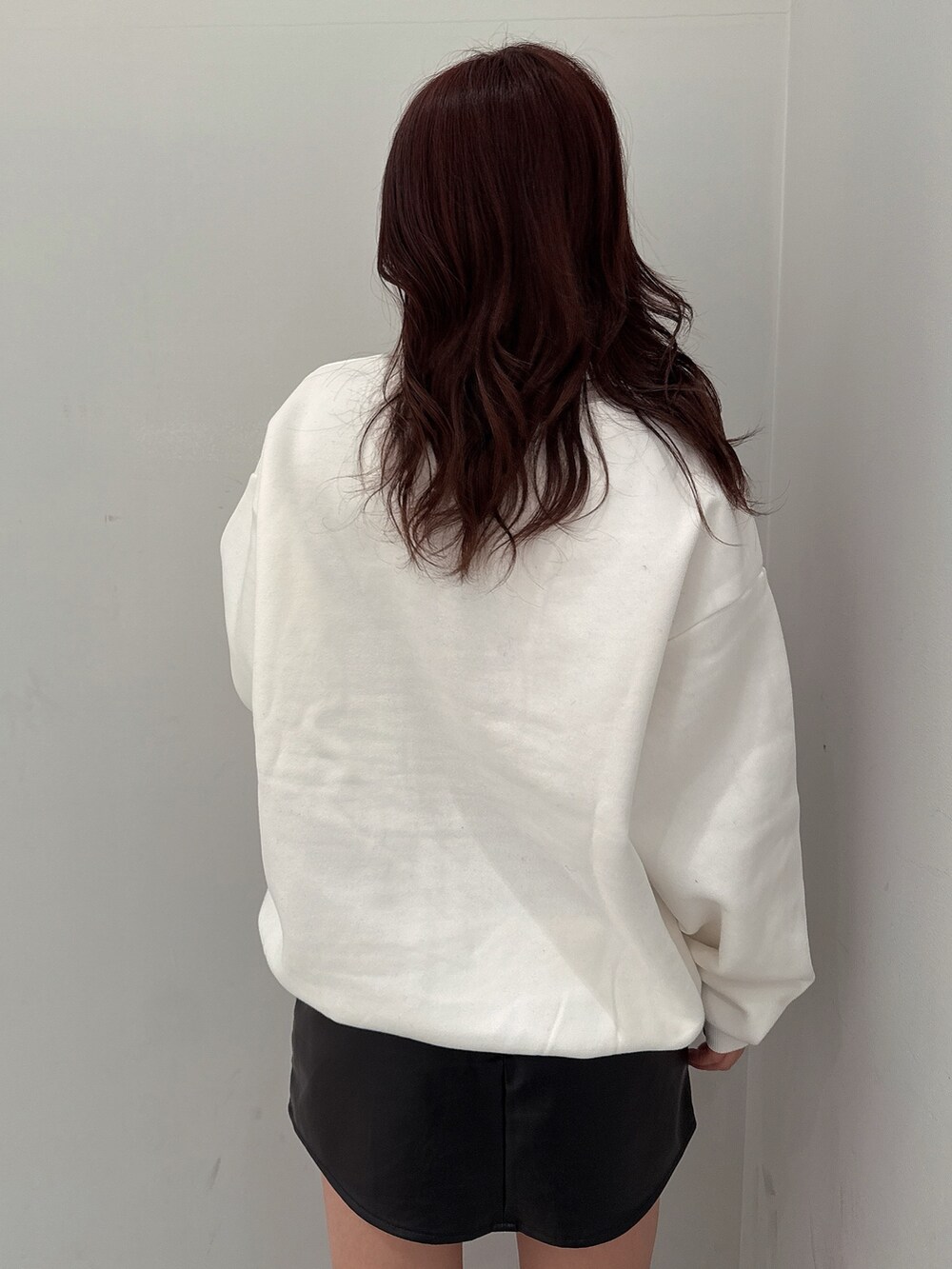 ブラック系のスカート、ブラック系のブーツ、ホワイト系のスウェットを着用したレディースの冬コーディネートの6枚目の写真