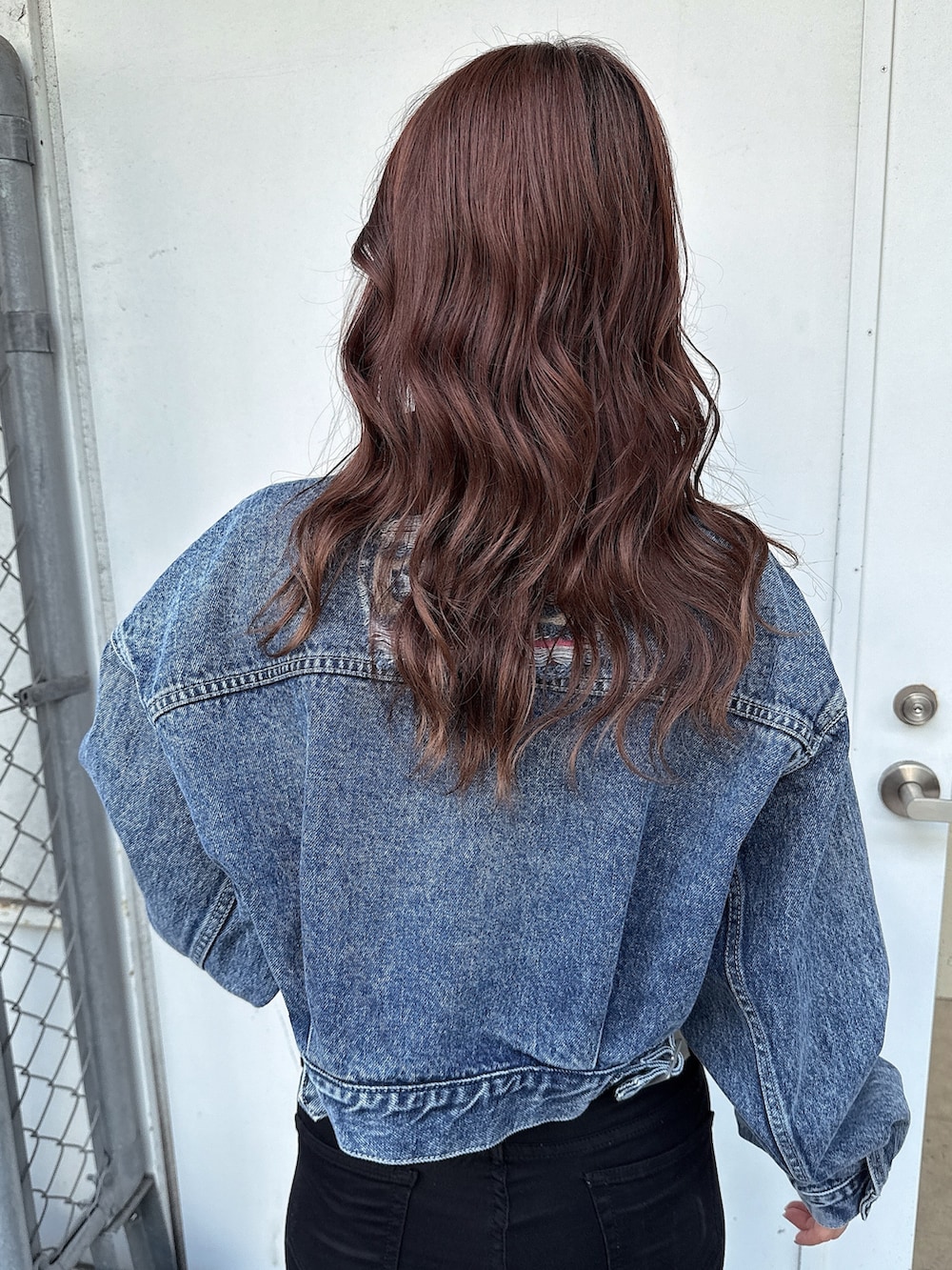 ブラック系のワンピース、ホワイト系のパンプス、ブルー系のデニムジャケットを着用したレディースの春コーディネートの6枚目の写真