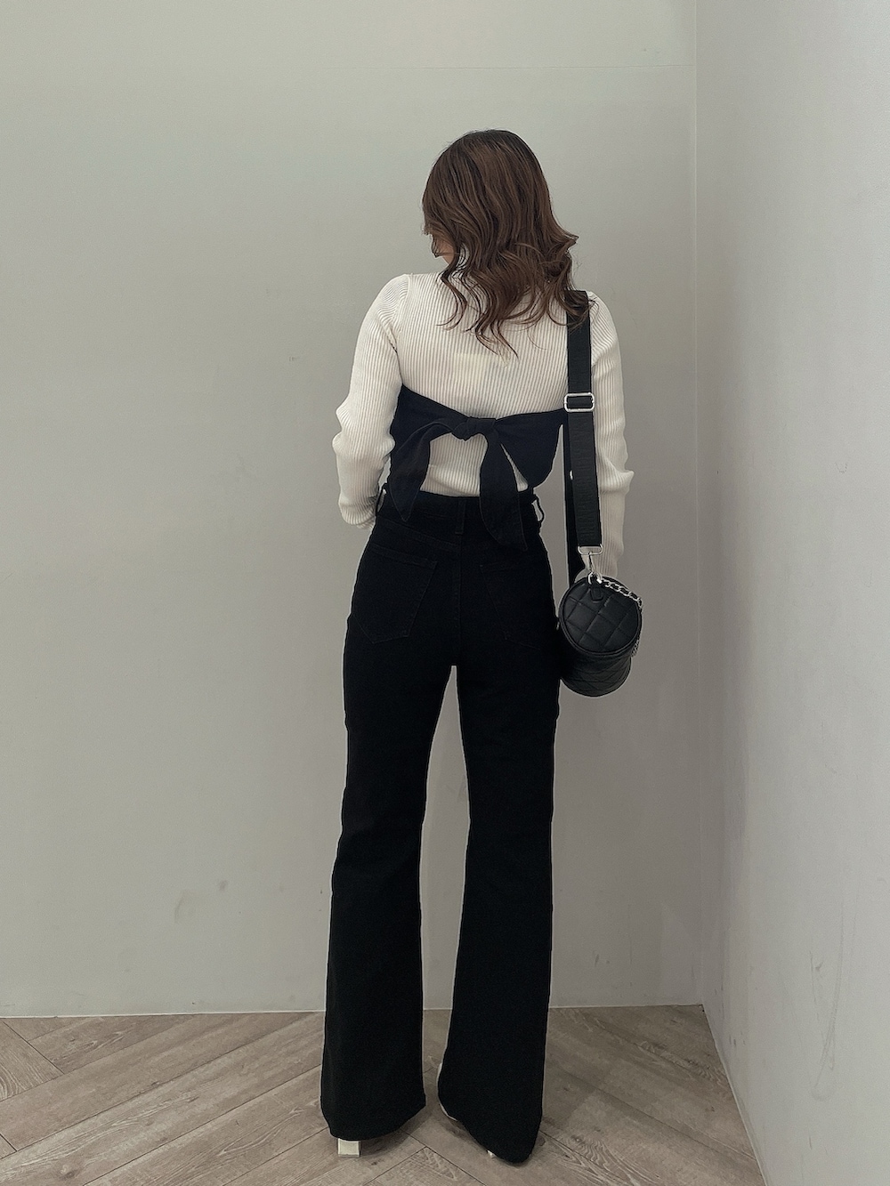 ホワイト系のニット/セーター、ブラック系のサロペット/オーバーオール、ブラック系のハンドバッグを着用したレディースの冬コーディネートの3枚目の写真