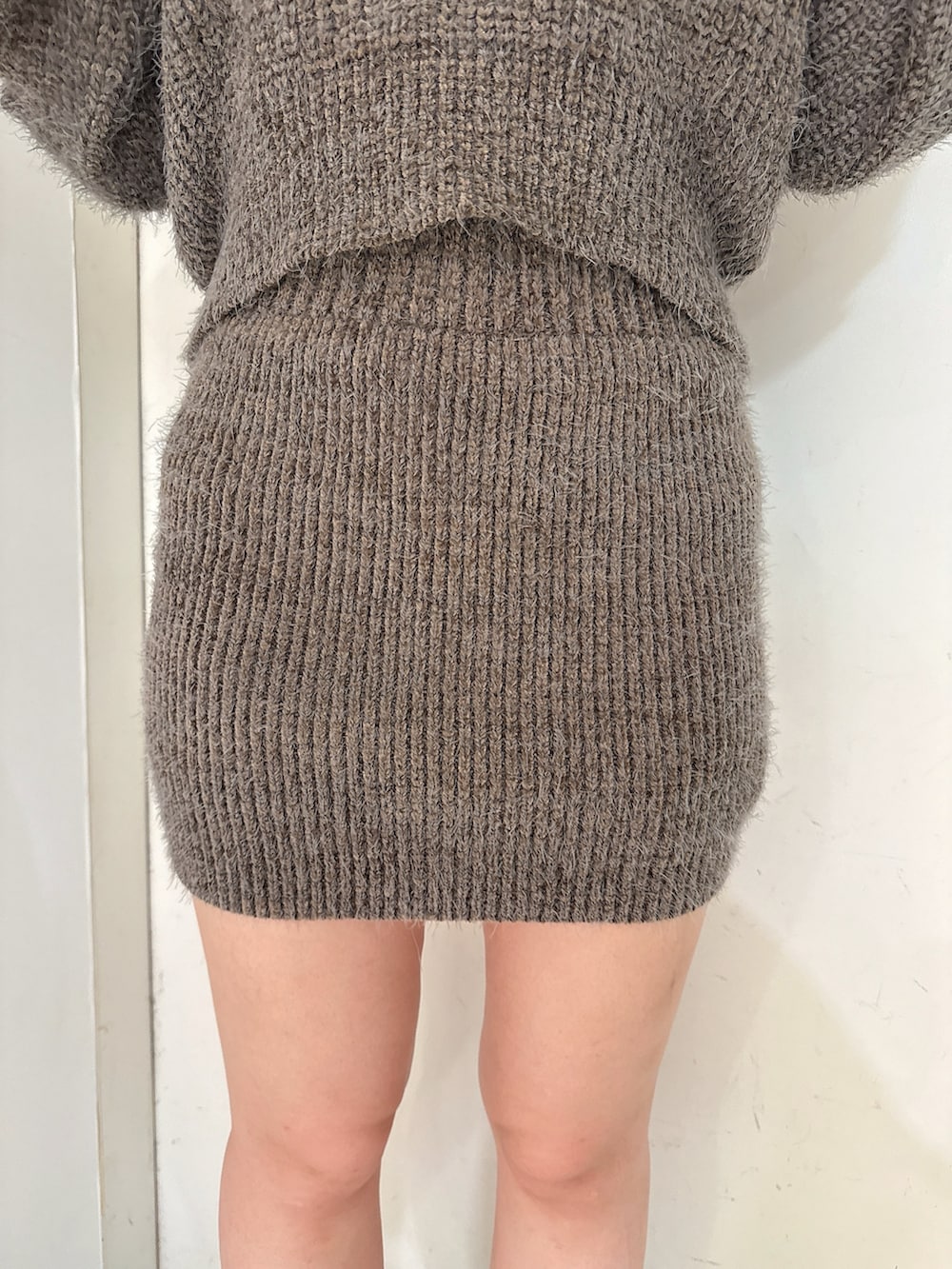 グレー系のニット/セーター、グレー系のスカート、ブラック系のブーツを着用したレディースの秋コーディネートの8枚目の写真